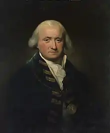 Half-length portrait of a grey-haired man in a navy blue jacket with gold buttons and braid, wearing a medal.