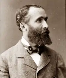 middle-aged white man with slightly receding dark hair and moderately bushy beard and moustache, seen in right profile