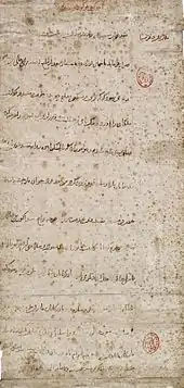 Long vertical mottled grey paper, with a dozen widely spaced lines of horizontal Arabic-looking script. There are two small oval red designs which have been stamped along the righthand margin of the paper.