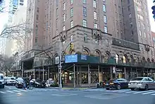 The Barbizon's ground-level facade as seen from the intersection of 63rd Street and Lexington Avenue. There are large archways with storefronts. On the right, there is scaffolding in front of the storefronts.