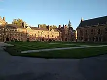 View over Liddon Quad covered in grass from the Chapel looking towards the Porter's Lodge. The building is the famous red brick.