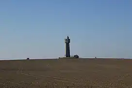 A folly on a hill in a ploughed field