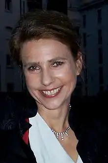 Middle-aged white woman with brown hair, grinning directly at camera