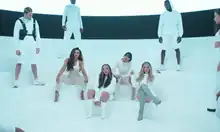 Little Mix on a stage in matching white outfits accompanied by dancers.