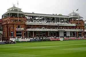 A brown coloured pavilion in front of a green field, surrounded by a number of banners