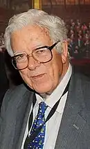 Colour photograph of Geoffrey Howe in grey suit and blue tie