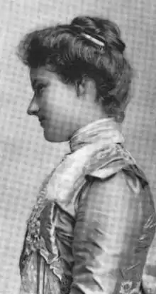 Young white woman in profile, wearing gown, hair pinned up.