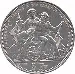 Seated Helvetia and Ticino. Helvetia is holding a sword and shield bearing the Swiss cross; Ticino is holding an oar with cantonal colours. The figures are seated above a the Gotthard tunnel with a steam engine emerging. Legend along edge at top, denomination at bottom.