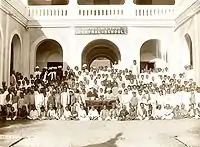 A group of students seated with a building in the background.