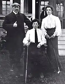 Three golfers, one man and two women, posed for an outdoor photograph.