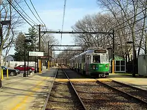 A green streetcar at a station