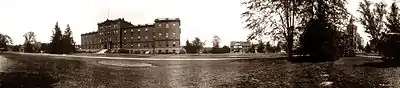 panorama of a large, multi-story building, with smaller buildings nearby