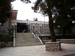 White building with stairs and a tree front of the entrance