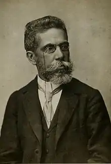  Man with moustache standing in suit and facing right