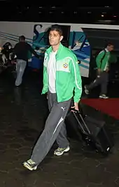 A white male leaving the bus wearing a Bulgaria national team tracksuit and pulling a suitcase behind him.