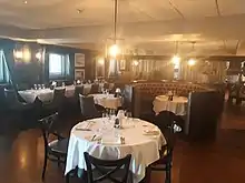 A brightly lit restaurant setting, with tables set, but no people.