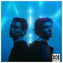 Marcus and Martinus standing back to back facing the camera in front of a lit blue wall that says "Air", with their logo superimposed in the bottom-right corner