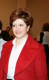 Brown-haired 50-year-old woman with red jacket and white blouse