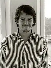 A black and white photo of young man with dark hair and a moustache