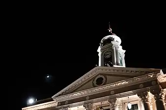 Top portion of portico, the tower and clock at night