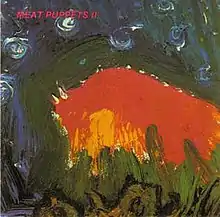 An abstract painting with thick swatches of green and blue framing a smaller area of red and orange. “Meat Puppets II” is printed in the upper left.