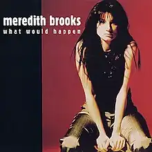 A portrait of Meredith Brooks sitting in front of a dark red and black backdrop, wearing a black sleeveless top and green plaid jeans. On the top-left of the portrait, Brooks's name and the song's title are depicted in white and tan text, respectively.