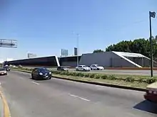 Picture of the station in the middle of Río Consolado Avenue. Several automobiles surround the station.