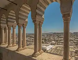 An old cityscape view seen through open Arabesque arches with the sea and a hill in the distant horizon