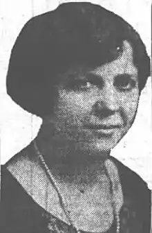 Portrait of a woman with bobbed hair in a dark dress wearing a long strand of pearls