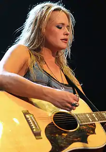 Miranda Lambert performing live and playing a guitar.