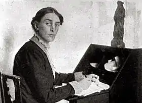 Youngish white woman with dark hair sitting at a bureau