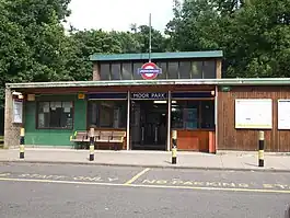 A red-bricked building with a rectangular, dark blue sign reading "MOOR PARK" in white letters and four black-striped posts in front