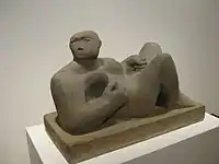 female figure carved out of green stone, lying with bent knees and turned head