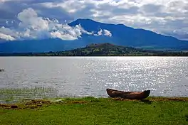 Lake with wooden canoe in foreground, mountain in distance.