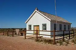 Plain white wooden school building with green trimmed windows