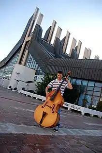 A boy with a Double bass on the terrace of the Palace of youth and sports in Pristina