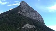 End of a mountain ridge seen in profile overlooking a wooded area.