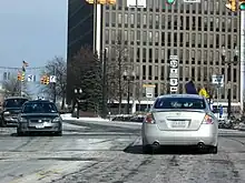 A driver's view of a four-lane highway in a commercial district.