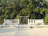 Raked gravel and a torii gate inside a concrete fence enclosure.