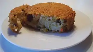 A nasischijf cut open showing the fried rice inside the deep fried snack