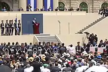 A man (Nayib Bukele) standing at a podium and speaking to a large crowd.