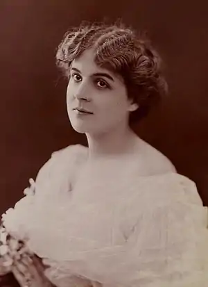 A white woman with pale skin and dark hair, wearing a white gown