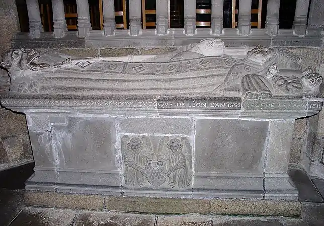 The gisant of Roland de Neufville,  Bishop of Léon  from 1562 to 1613. He wears a bishop's robe and mitre and the cushion on which he rests his head is supported by two angels. There is a dragon at his feet.