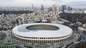 Large white stadium against backdrop of a city