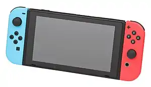 The Nintendo Switch in handheld mode. The center tablet is black, and attached on both sides are Joy-Con controllers. The left Joy-Con is blue, with several buttons. The right Joy-Con is red, with several other buttons.