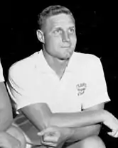 Norm Sloan, 35-year-old white man, shown in white shirt and coaching shorts, kneeling for team photo.