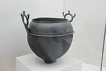 A bronze cauldron with two handles and three mushroom-like ornaments on each handle