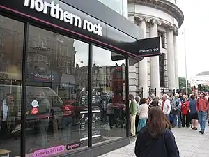 A number of people queuing at the door of a branch of the Northern Rock bank.