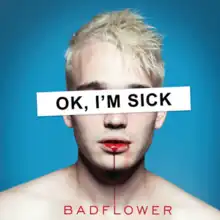 The cover has a blue background that's occupied by a blonde-haired man with blood dripping from his mouth into the band's name. A white background with the album title is covering the man's eyes.