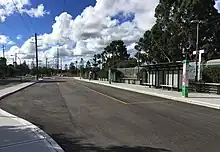 Bus-only road with four bus stops on the side next to a railway platform in the back